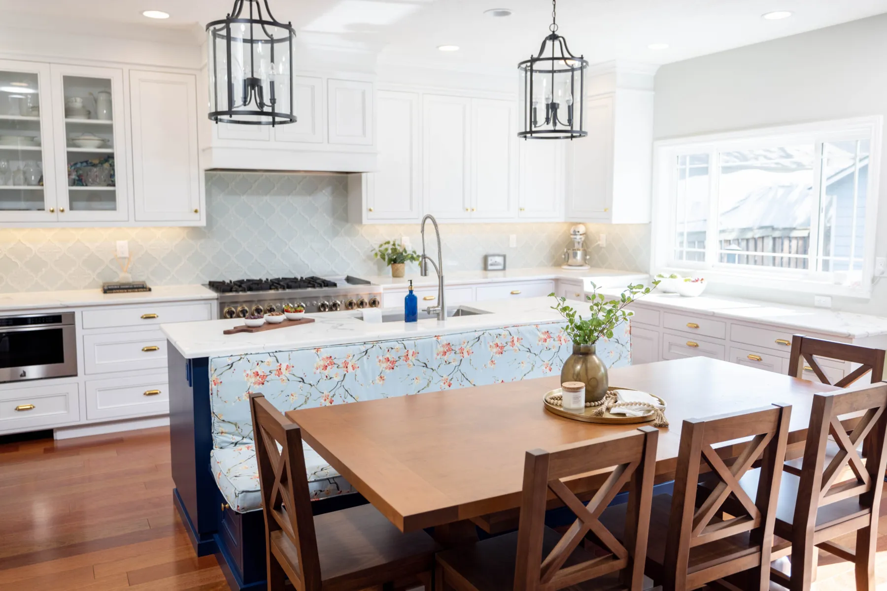 The finished Davis kitchen — white cabinetry, a navy island with a cherry-blossom bench cushion and black lantern pendants