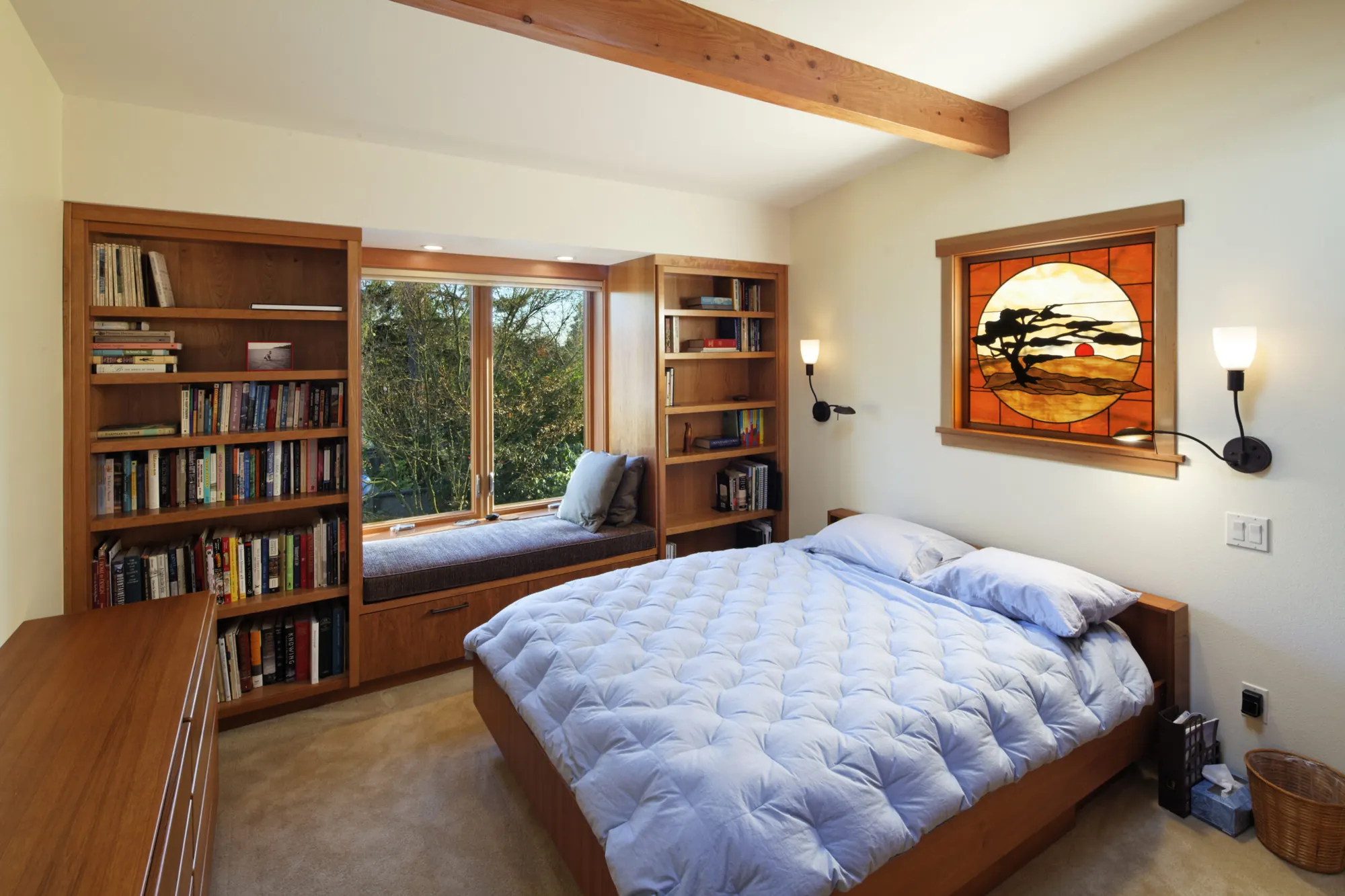 A bedroom fully planned with custom built-in bookcases, a window seat and layered lighting