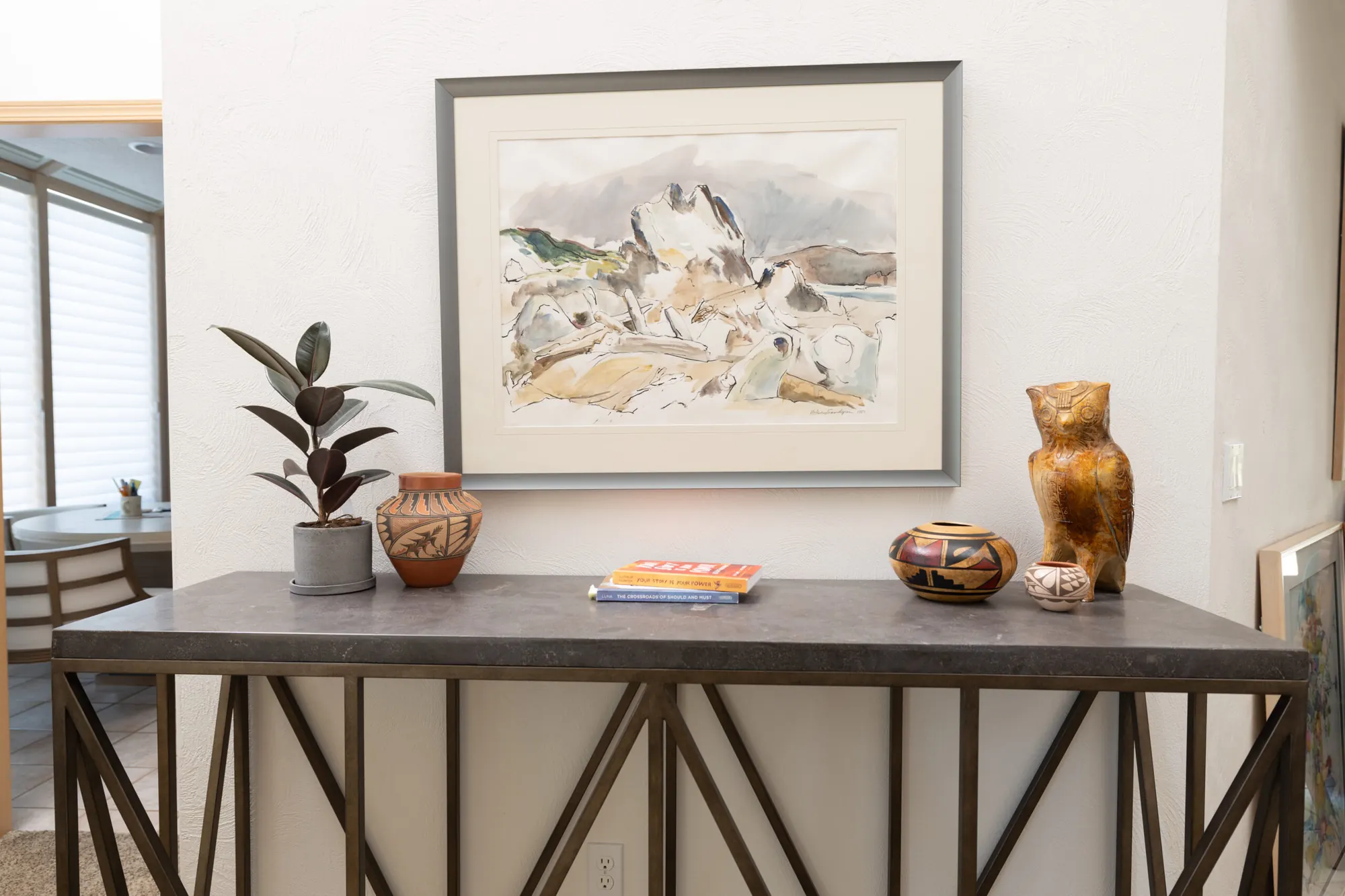 A styled console table with sourced framed art, pottery and objects