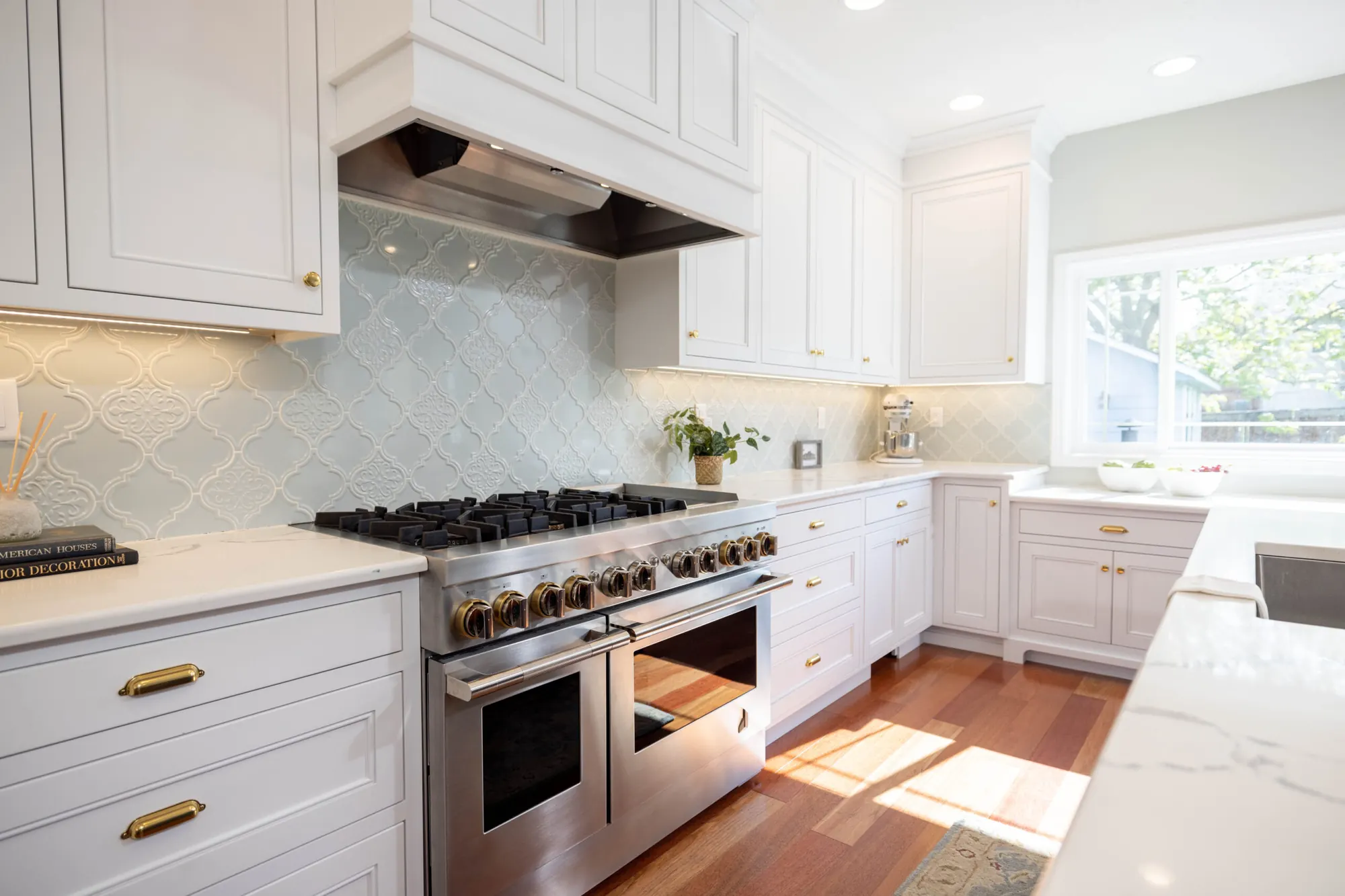 A finished Kalluna-designed kitchen with light cabinetry, a tile backsplash and warm wood flooring