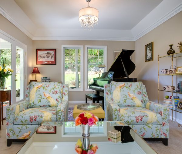 Bird-patterned chairs bring color and personality to this light-filled living room, where the piano, art, and collected details make the space feel deeply personal.