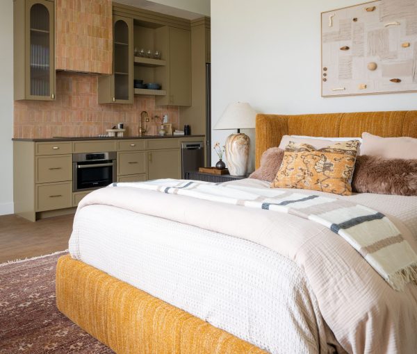 Bedroom with built-in wood cabinetry, bed with white and mustard bedding, patterned pillows, and framed wall art.