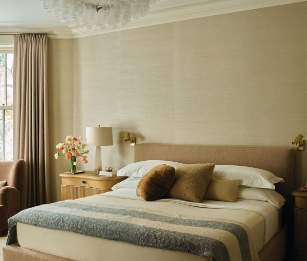Bedroom with upholstered bed, neutral bedding, bench, bedside tables, drapery, and chandelier